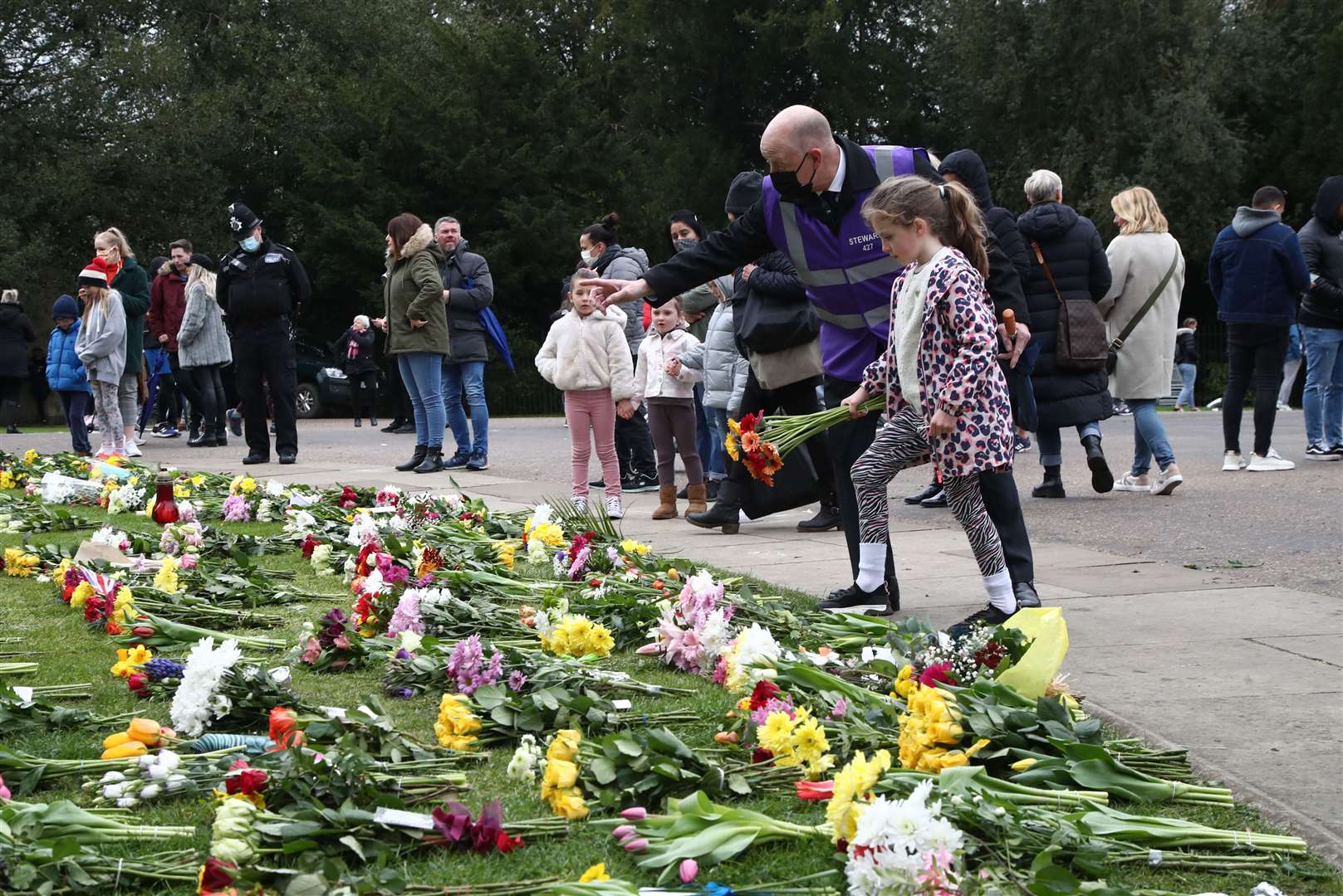 A young girl is directed where to place flowers outside Windsor Castle (PA)