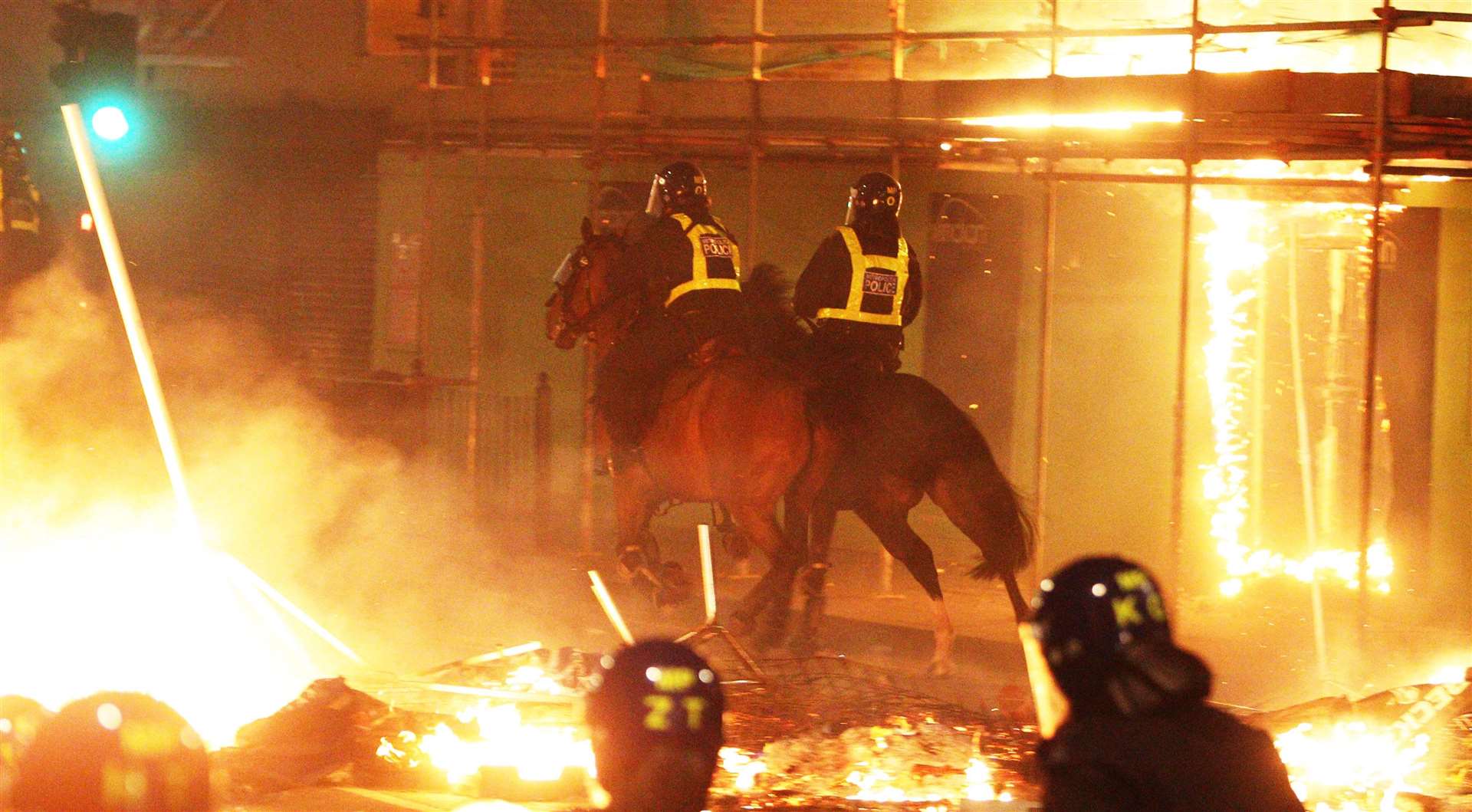 File photo of mounted police on the streets in Tottenham, north London as fire burns around them during riots. (Lewis Whyld/PA)