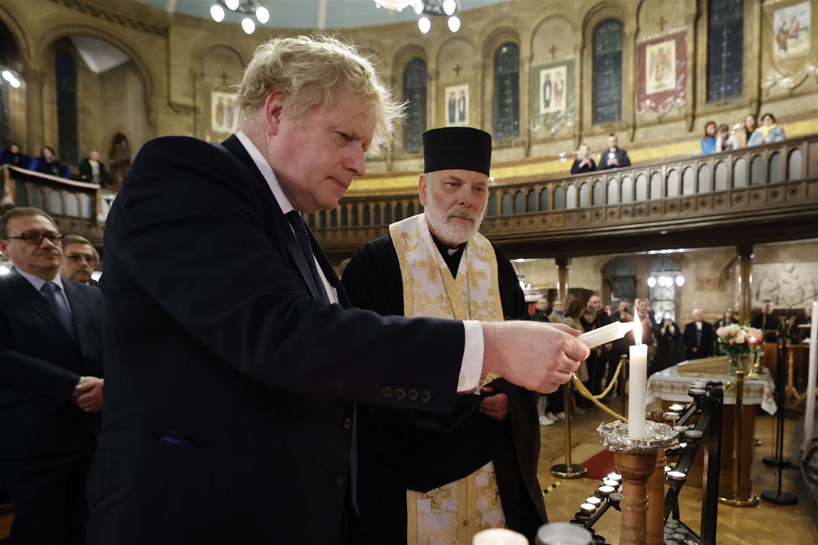 British Prime Minister Boris Johnson (left) lights a candle during a visit to the Ukrainian Catholic Eparchy of Holy Family of London (PA/Jamie Lorriman)