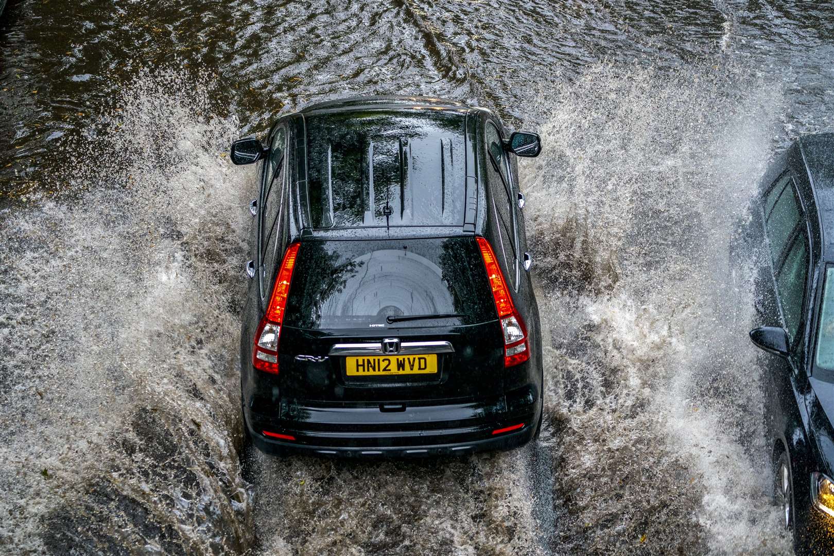 A car drives through standing water in Gateacre, Liverpool in August 2021