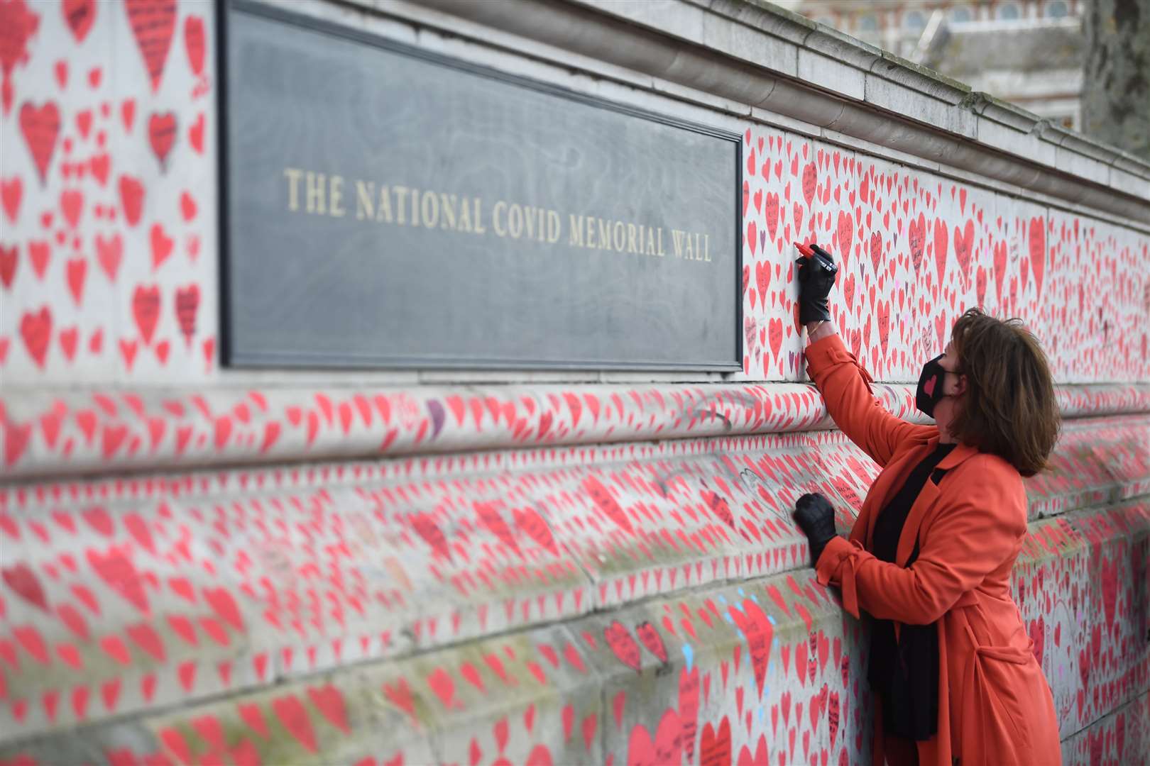 Fran Hall, who lost her husband to coronavirus, helps with the painting approximately 150,000 hearts on the National Covid Memorial Wall in central London (Victoria Jones/PA)