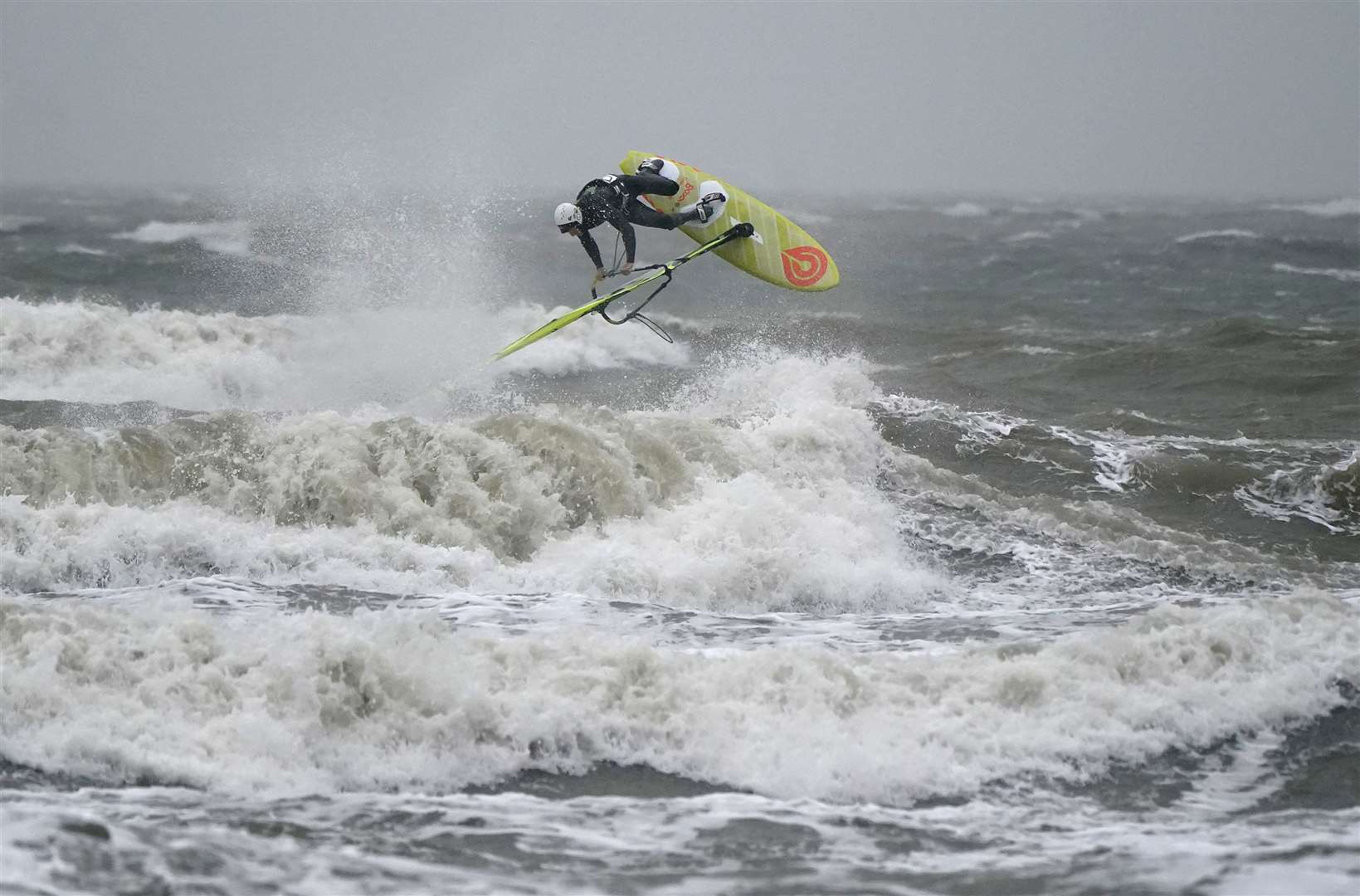 A wind surfer surfs a wave as they take to the sea during high winds in Bracklesham Bay, West Sussex (Andrew Matthews/PA).