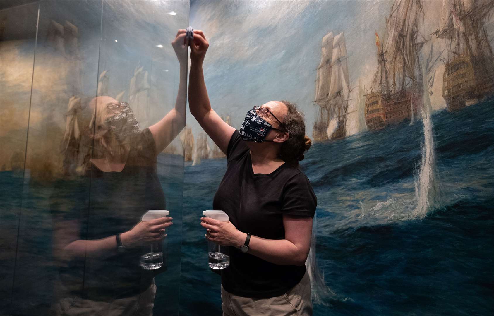 Alison Firth, curator of art at the National Museum of the Royal Navy, cleans the glass window in front of WL Wyllie’s Panorama of the Battle of Trafalgar (Andrew Matthews/PA)