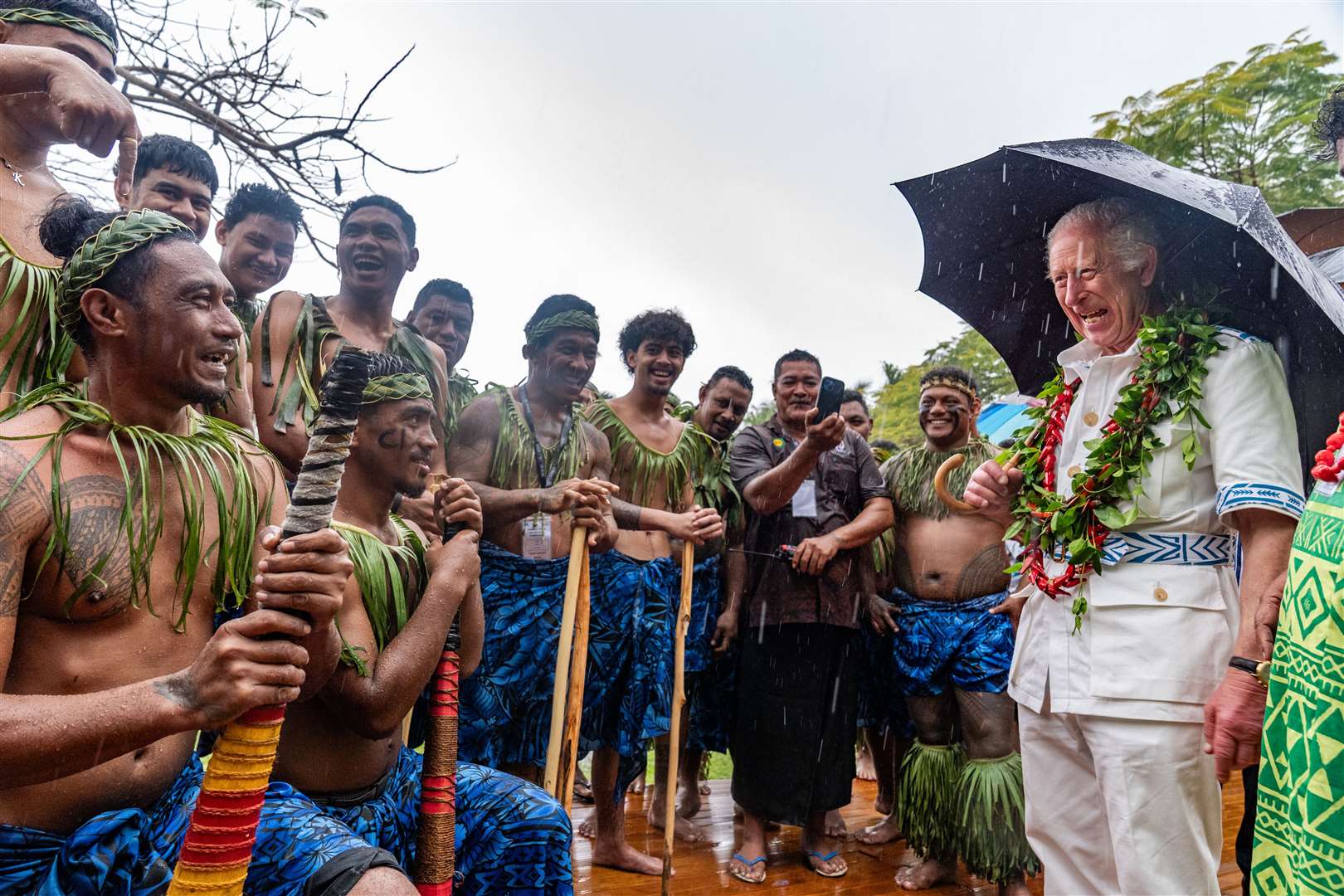 The King shares a joke with members of a cricket team during a visit to the Samoan Cultural Village in Apia (Aaron Chown/PA)