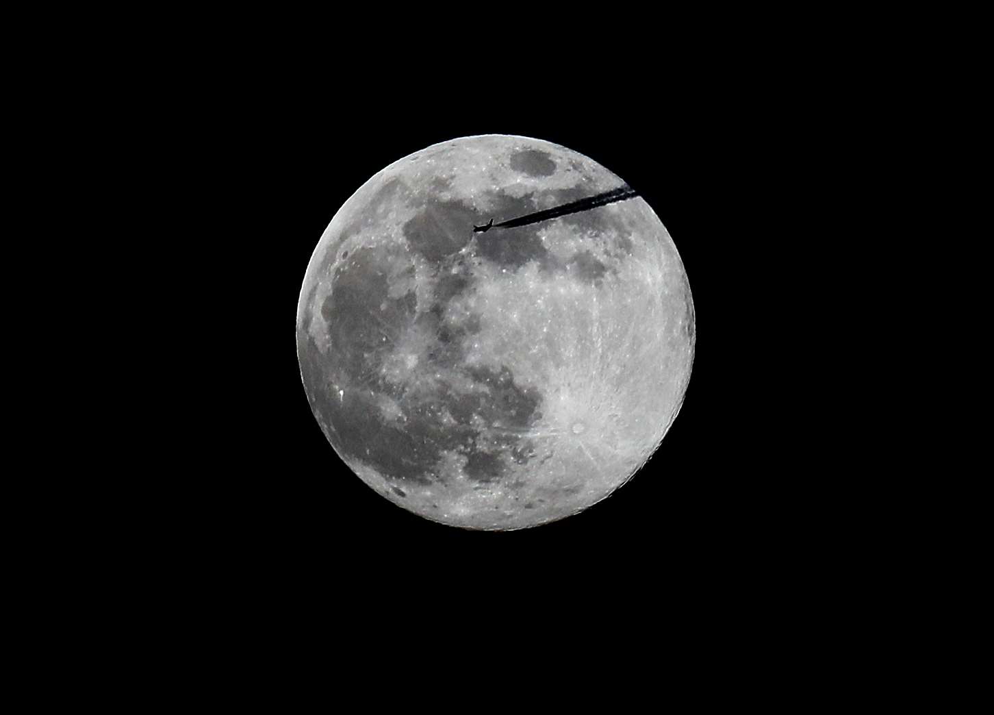 A plane passes the pink supermoon as it rises over Dublin (Brian Lawless/PA)