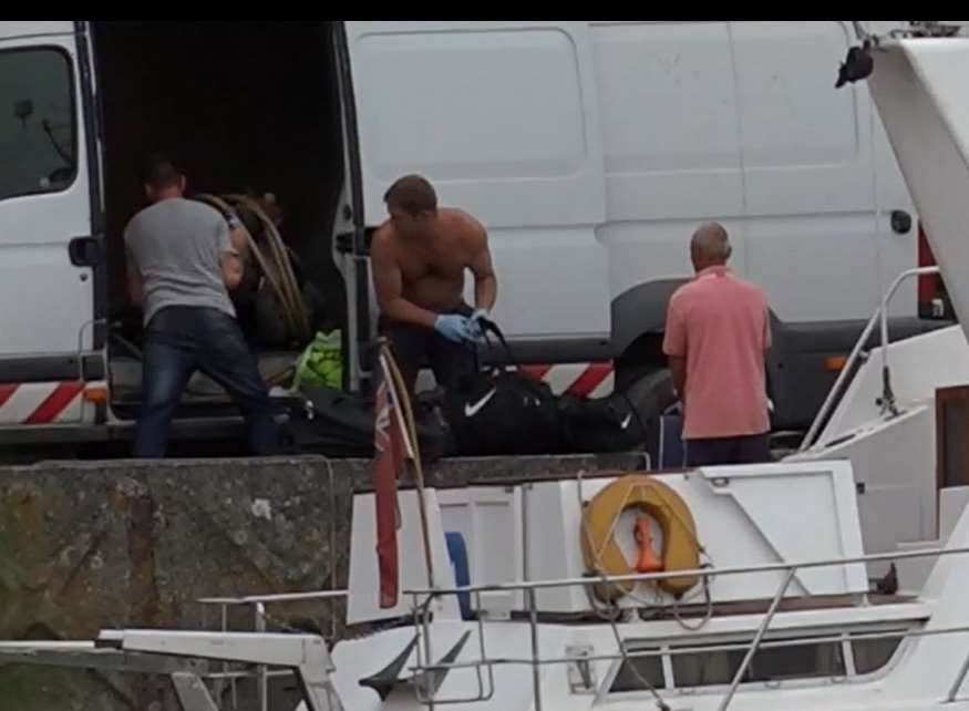 The bags are loaded from the boat into a white van