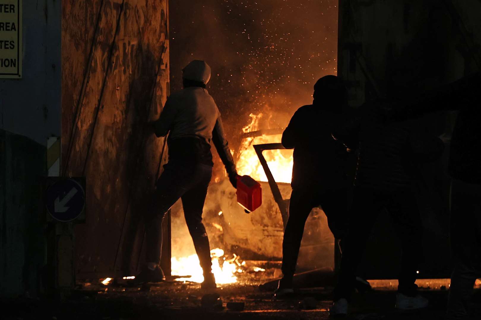 A nationalist throws a petrol canister at the Peace Gates in Lanark Way, Belfast (Liam McBurney/PA)