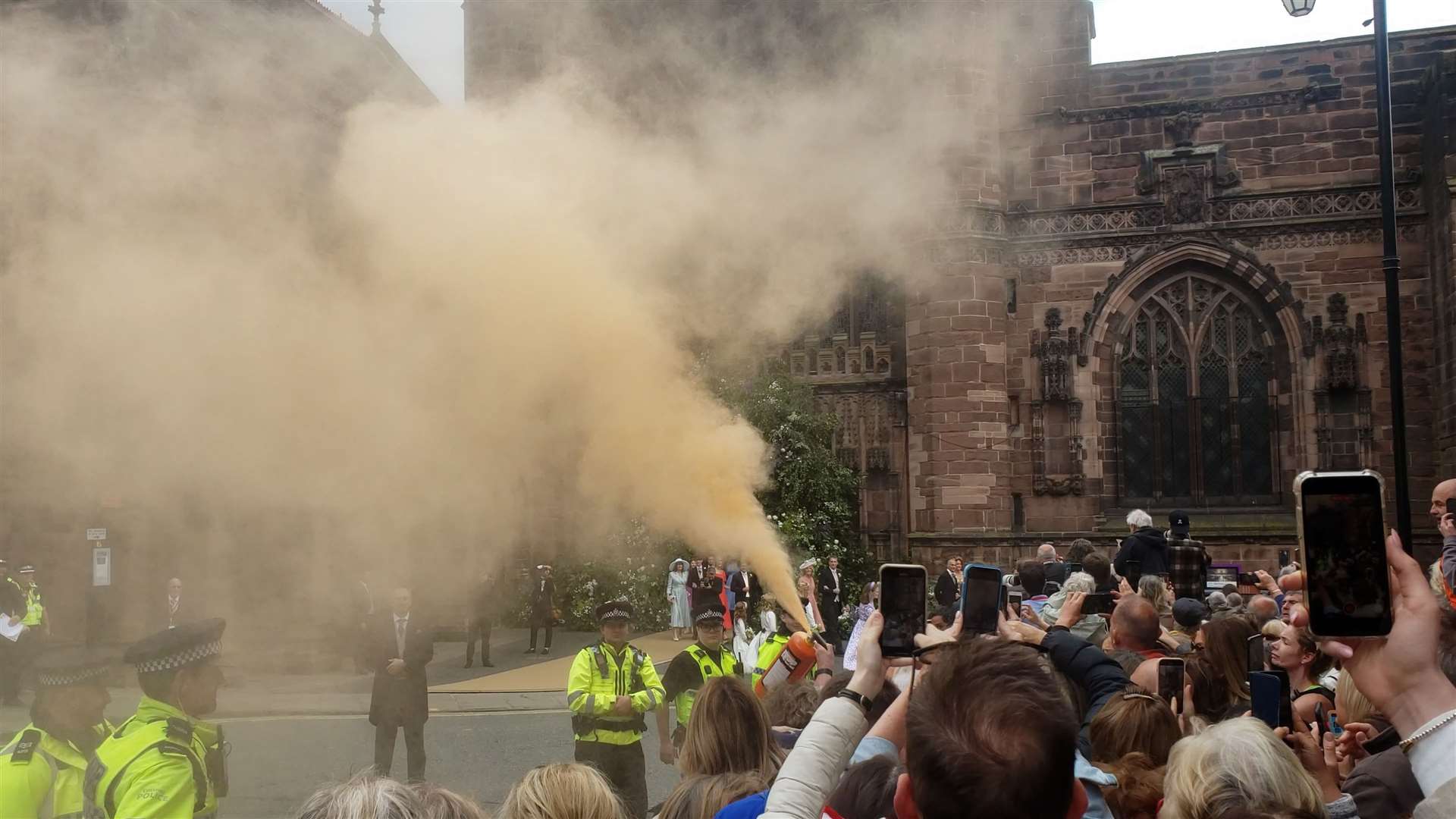 A protester using a fire extinguisher to project powder paint outside Chester Cathedral during the wedding of Hugh Grosvenor, the Duke of Westminster, and Olivia Henson (Just Stop Oil/PA)