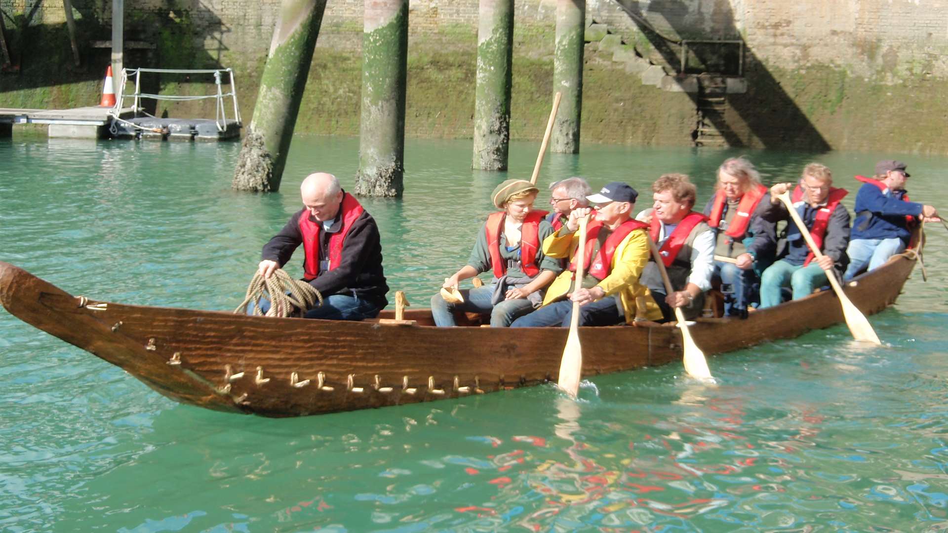 The crew row the replica of the Bronze Age Boat out of the dock.