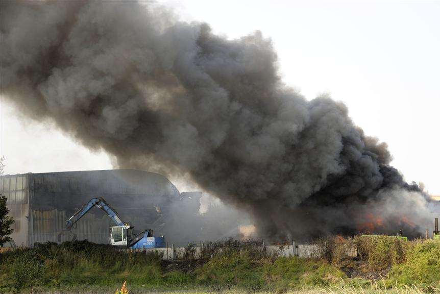 Smoke billows into the sky as a mechanical loader is used to move material away from the fire. Picture: Andy Payton