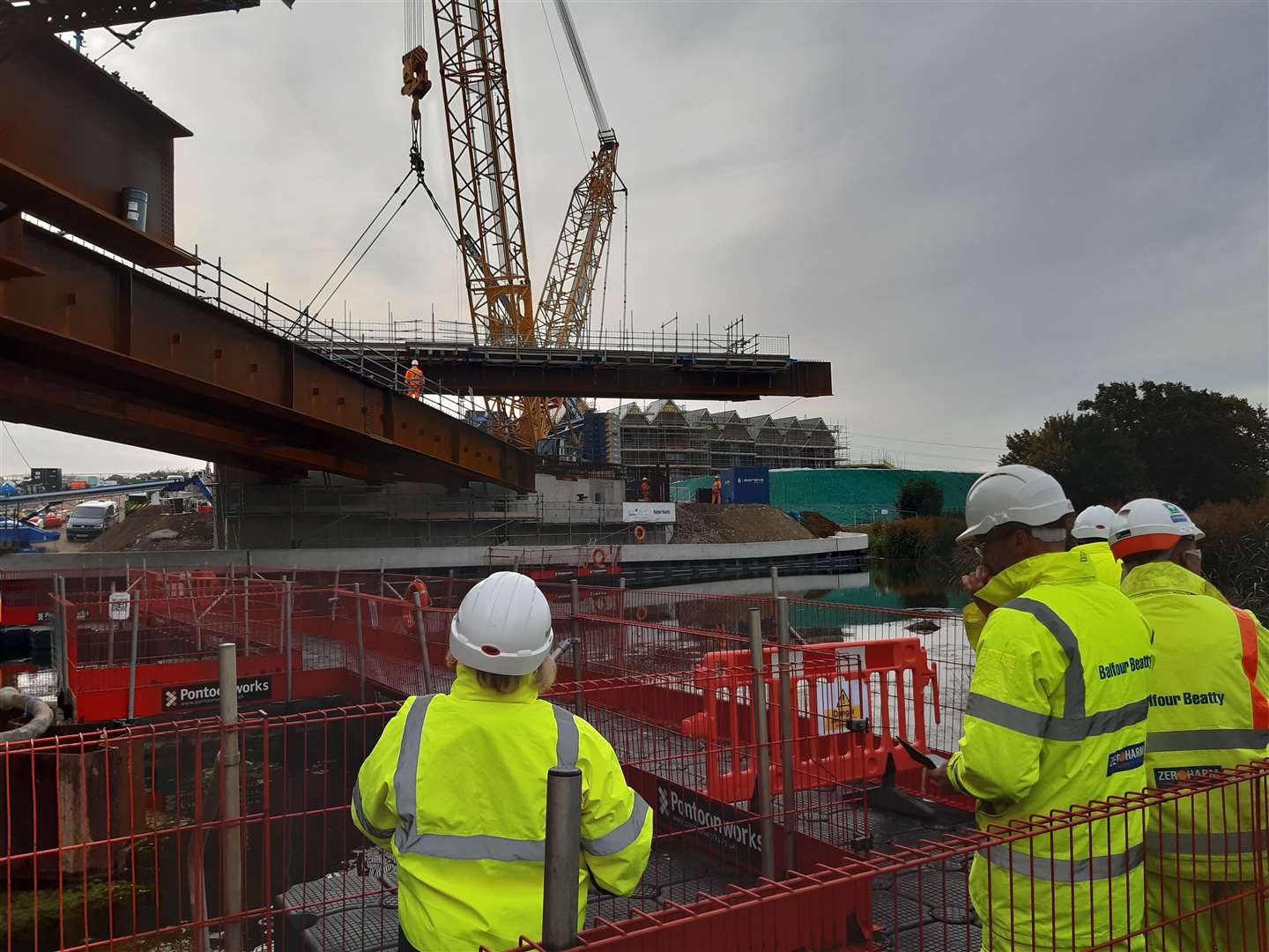 Construction workers look on as the sixth and final beam is lifted by the crane. (18383813)