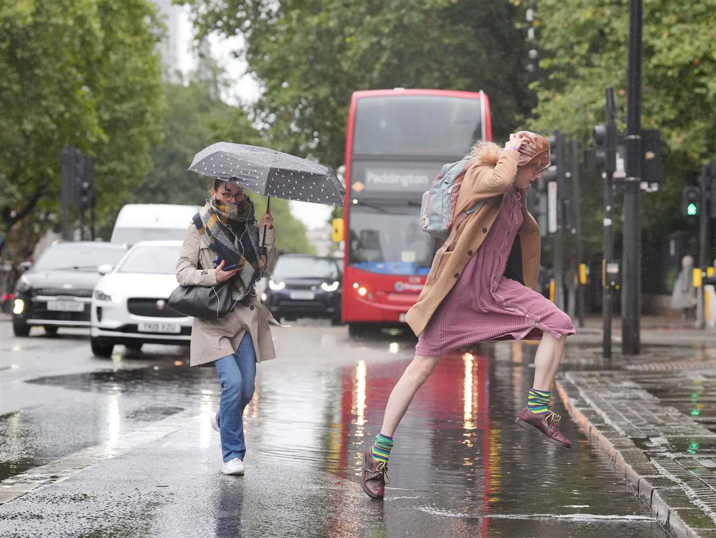 A woman jumps over a puddle (Jonathan Brady/PA)