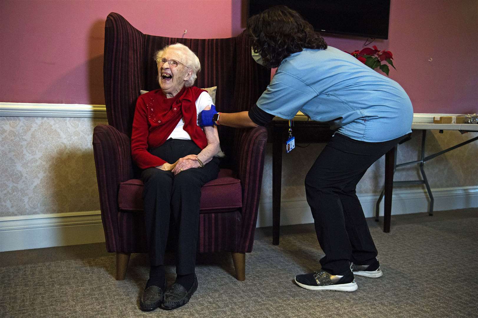 Ellen Prosser, known as Nell, who is 100 years old, receives the Oxford/AstraZeneca vaccine from Dr Nikki Kanani at the Sunrise Care Home in Sidcup, south-east London (Kirsty O’Connor/PA)