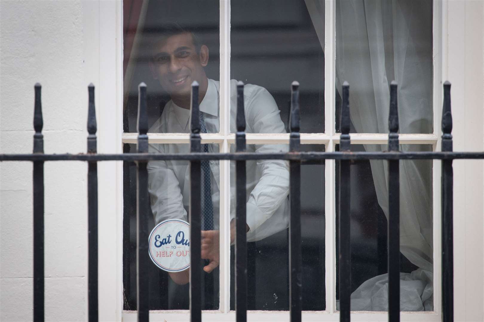 Chancellor Rishi Sunak places an ‘Eat out to help out’ sticker in the window of No.11 Downing Street before its start on Monday (Stefan Rousseau/PA Wire)