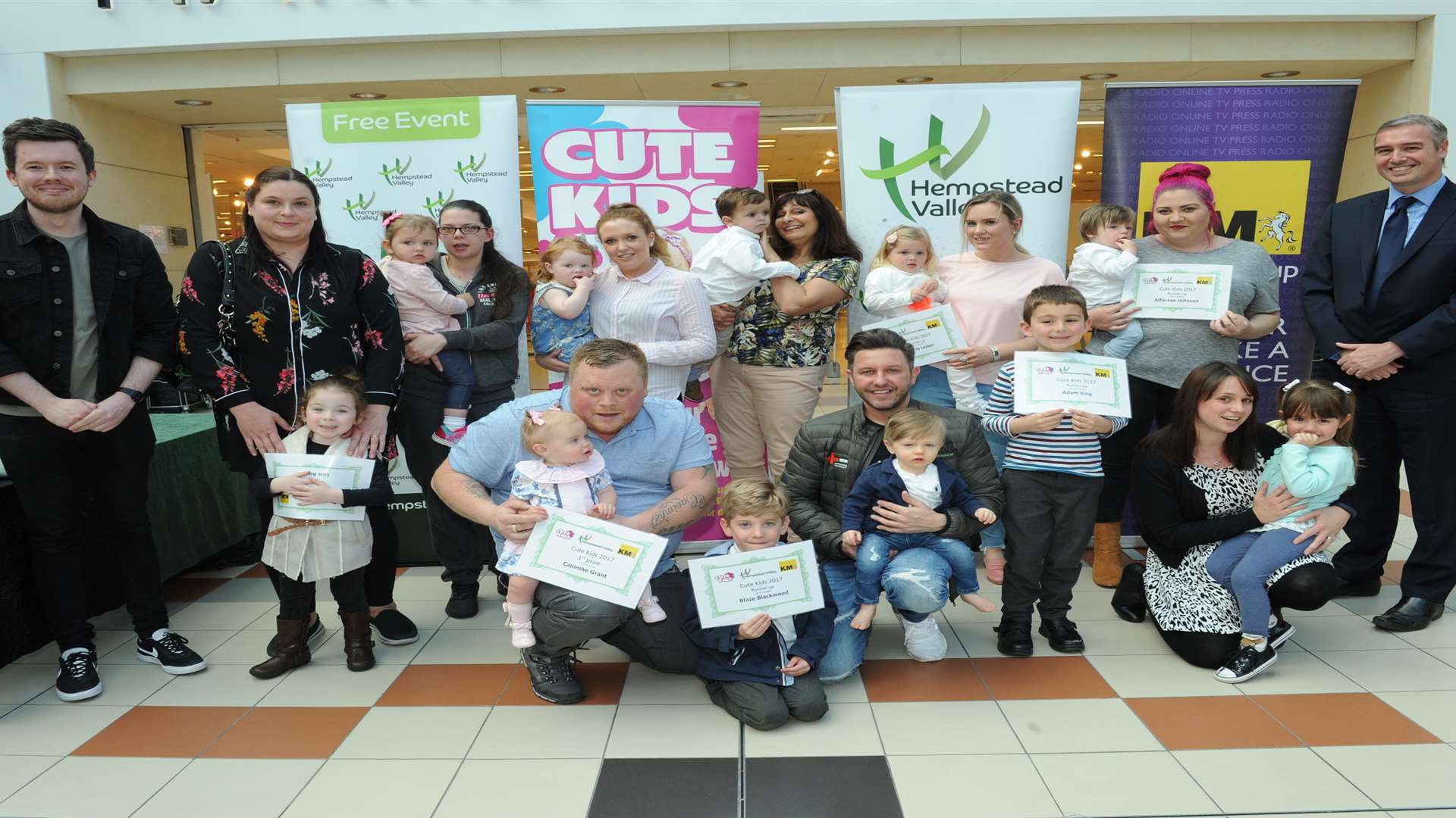 All of the Cute Kids winners and their parents with Medway Messenger editor Matt Ramsden, Mark Rumfitt, centre manager and Glenn Scott from kmfm