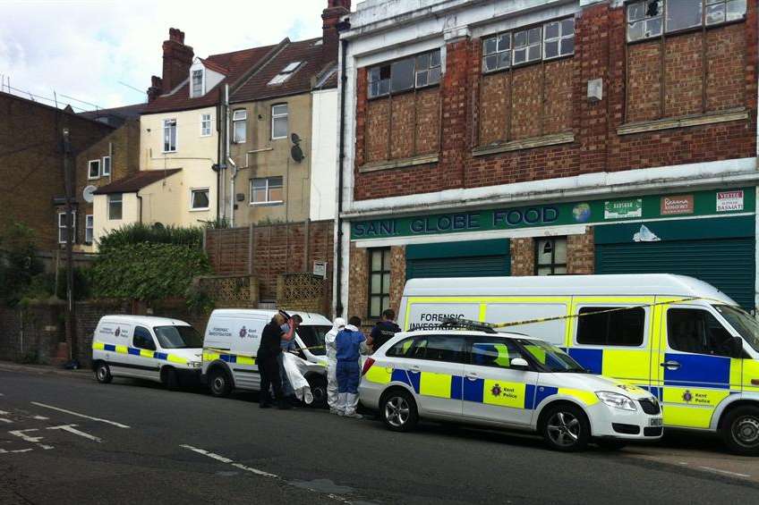 Police at the back of the Sani Globe Food store after Mrs Chaggar's body was found