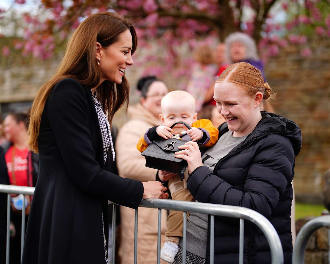 Lucy Williams, from Aberfan, holds her son Daniel as he takes the handbag of the Princess of Wales (Ben Birchall/PA)