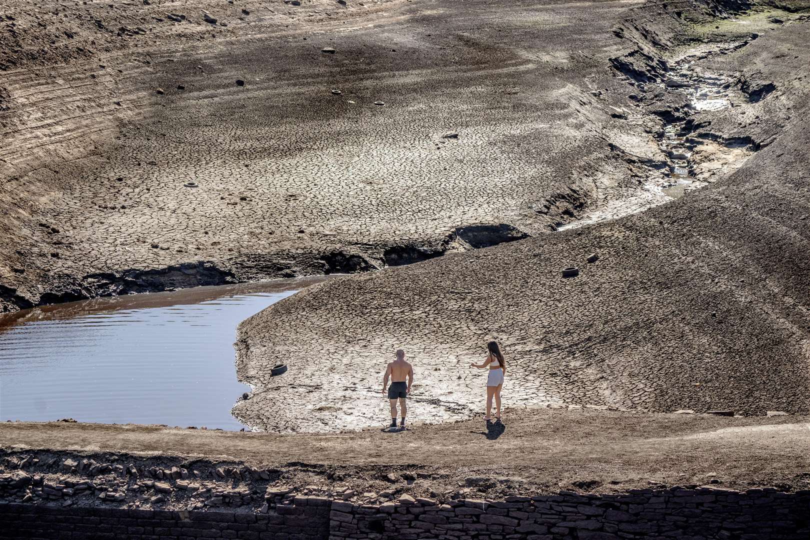 People walk on the dry cracked earth at Baitings Reservoir in Ripponden, West Yorkshire (Danny Lawson/PA)