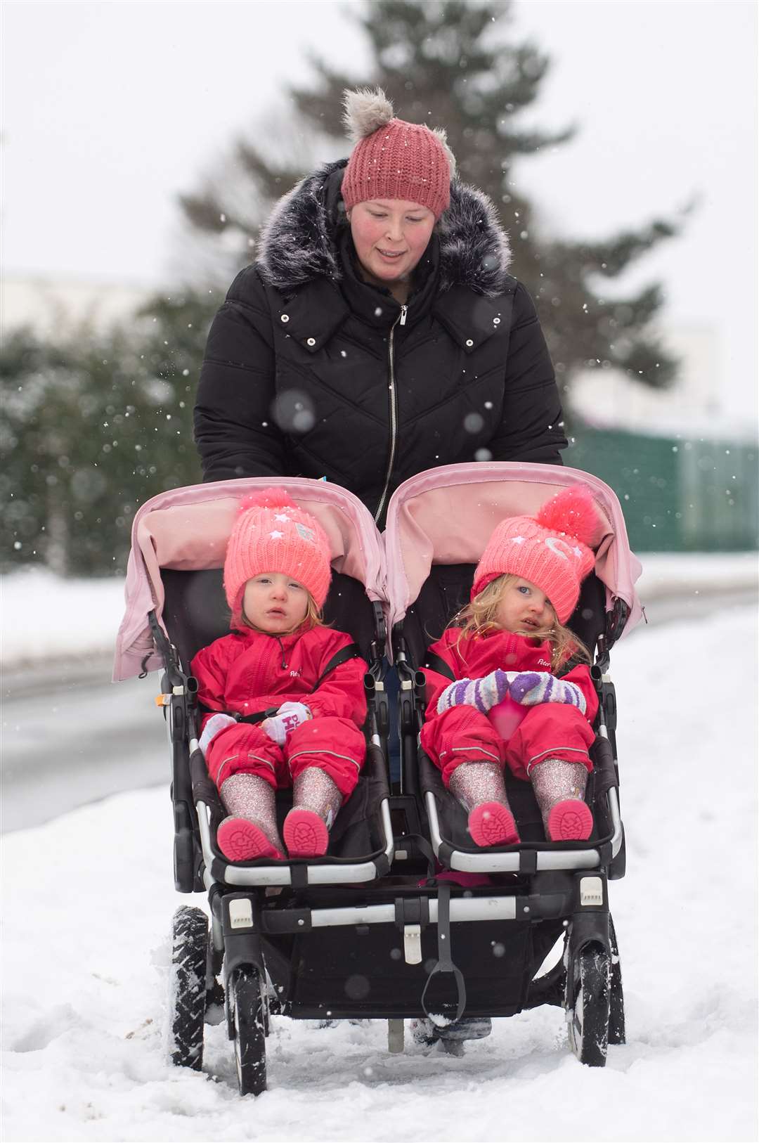 A mother pushes her twins through the snow in their buggy in Ipswich (Joe Giddens/PA)