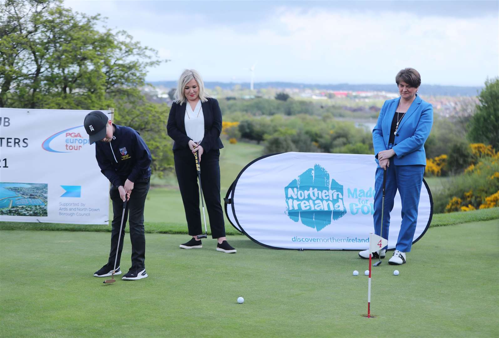 Arlene Foster and Michelle O’Neill watch Harry O’Hara, 12, at Clandeboye Golf Club near Bangor (Niall Carson/PA)