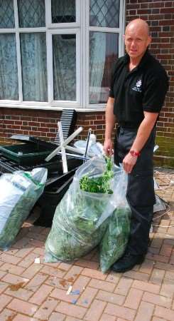 A member of Margate police's tactical team brings out bags of cannabis plants from the house at 50 Hartsdown Road, Margate