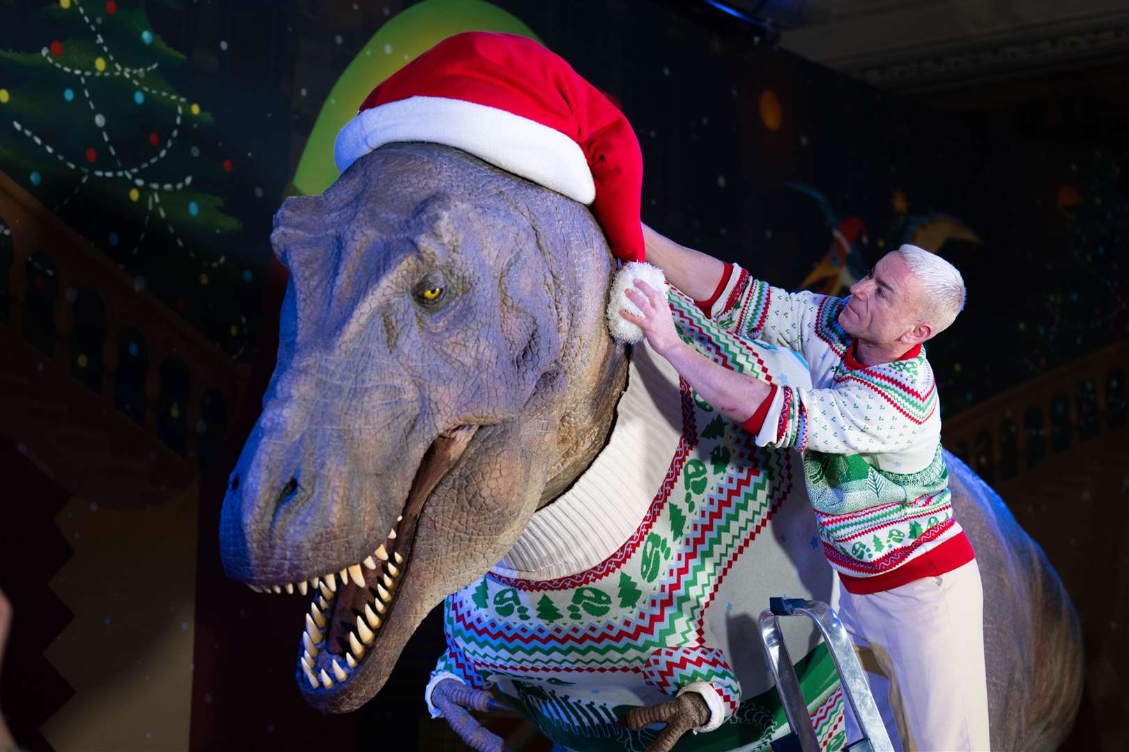 A member of staff adjusts a giant Santa hat at the unveiling of the Natural History Museum’s 2024 Christmas jumper (James Manning/PA)