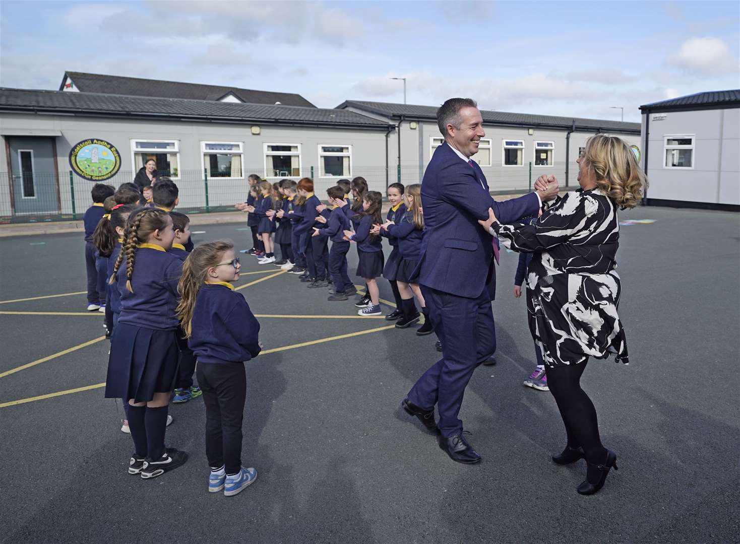 Paul Givan takes part in a ceili dance with principal Mona Ui Dhochartaigh (Niall Carson/PA)