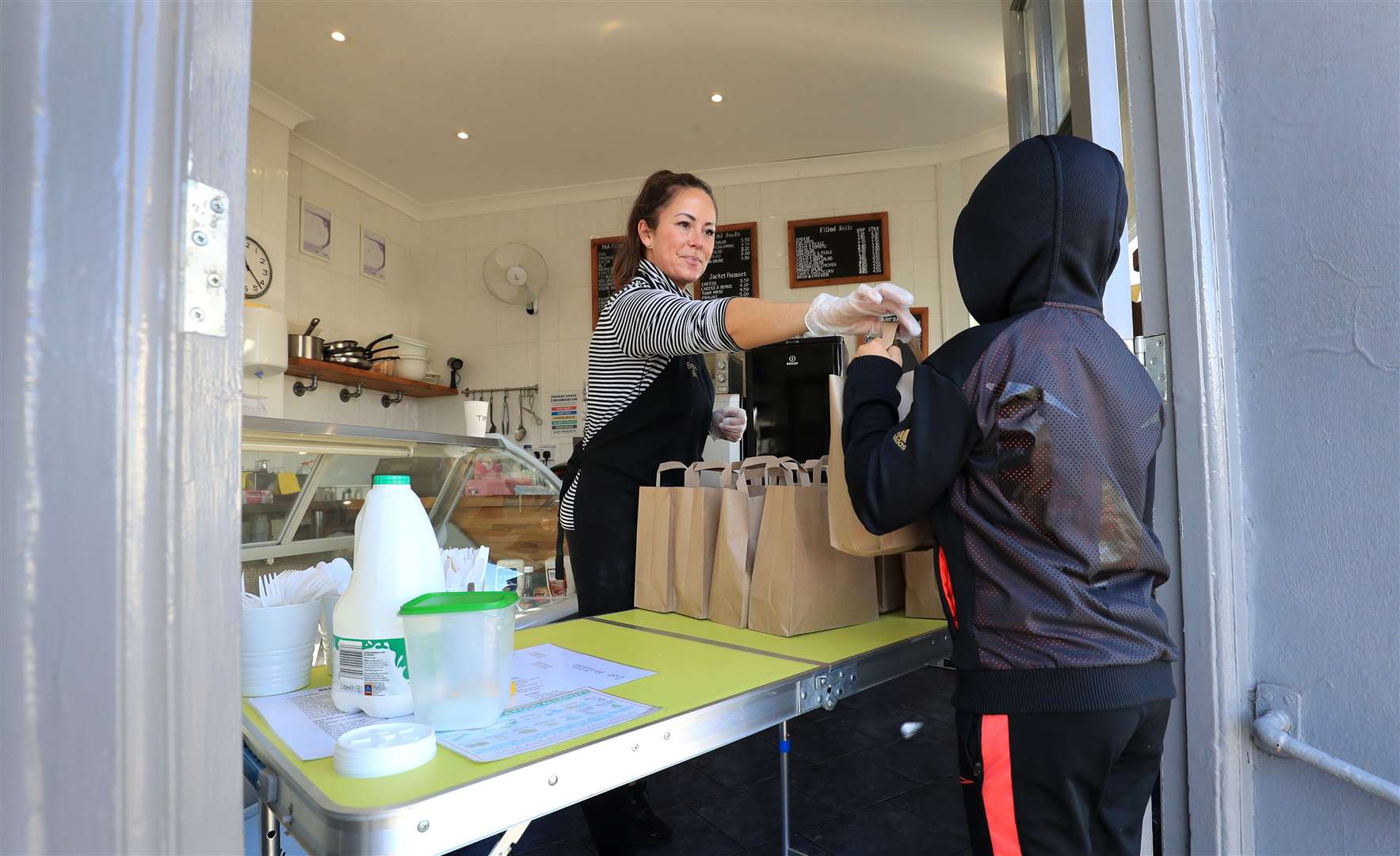 Sarah Marriott, co-owner of the Brunch Box in Deal, Kent, hands a lunch pack to a young person (Gareth Fuller/PA)