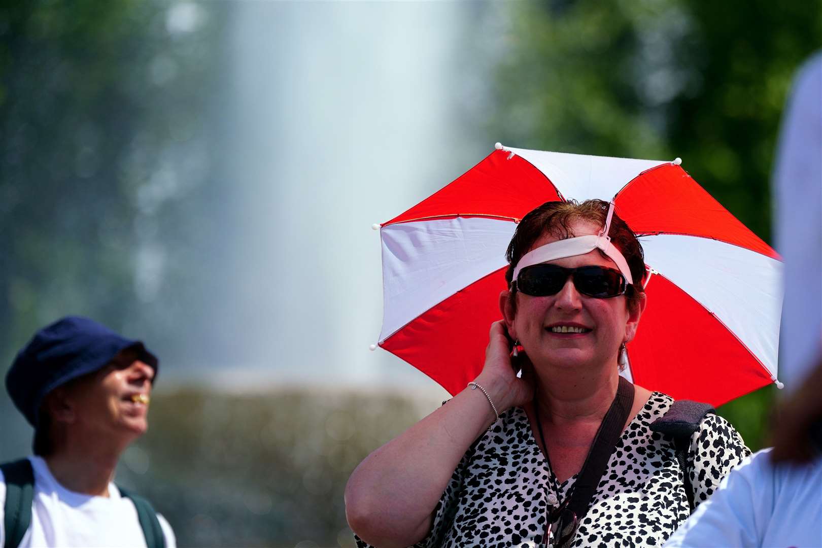 A woman wears an umbrella shield on her head during hot weather in Trafalgar Square (Victoria Jones/PA)