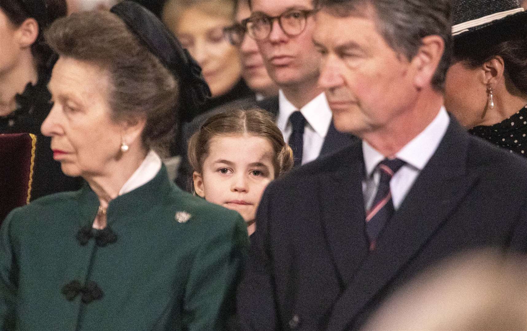 Princess Charlotte peers out from her seat behind the Princess Royal and her husband Vice Admiral Sir Tim Laurence (Richard Pohle/The Times/PA)