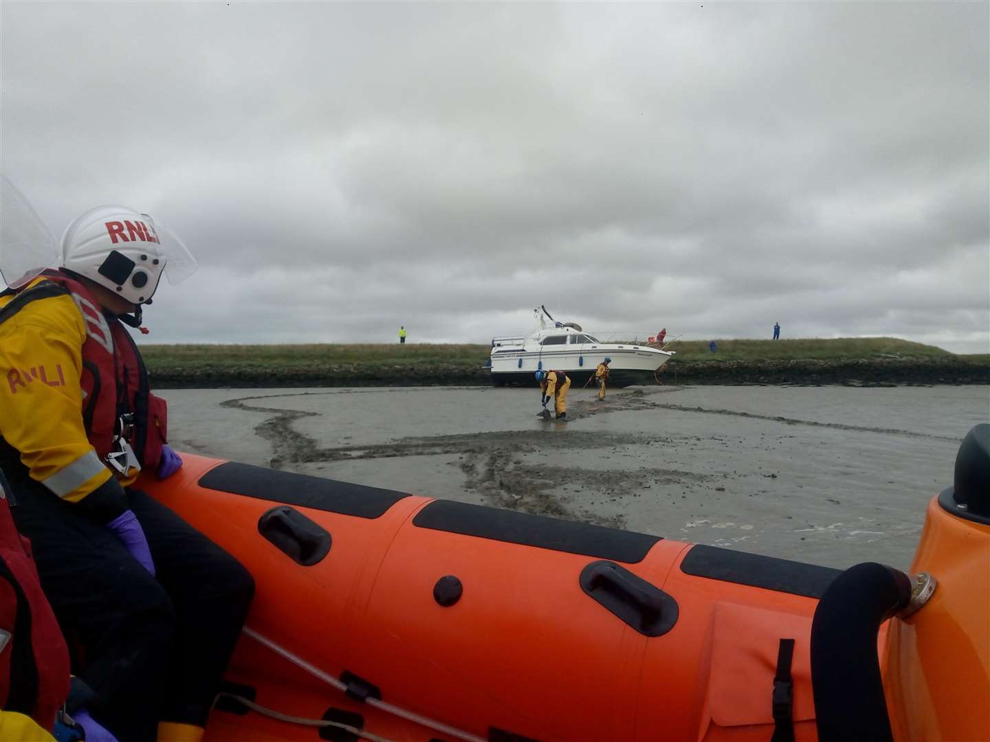 Seen from the Whitstable lifeboat, members of the Sheppey Mobile Coastguard team wearing mud rescue gear reposition the anchor from the motor cruiser aground near the sea wall on the Sheppey side of The Swale opposite Ridham Dock on Saturday morning. Picture: Dave Parry/RNLI Whitstable.
