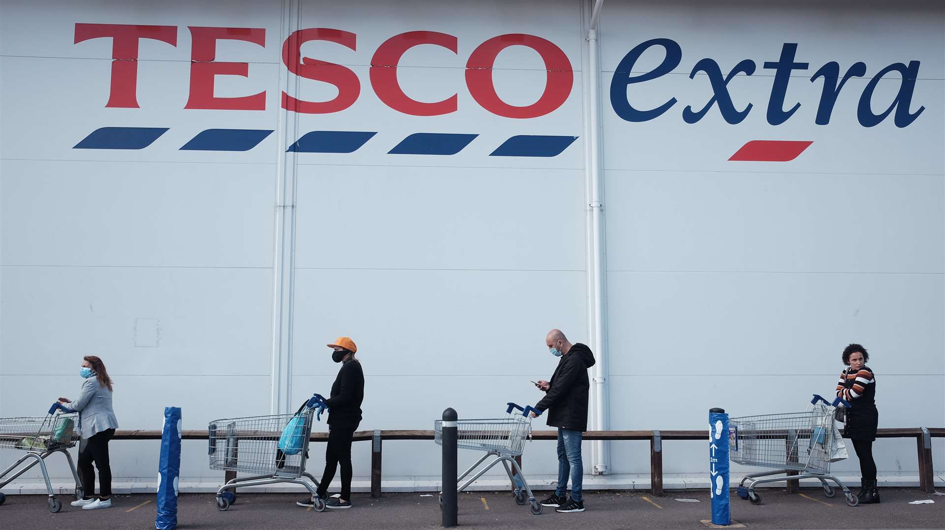 People practice social distancing outside a Tesco Extra store (Yui Mok/PA)