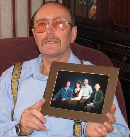 Philip Maling holds a picture showing his wife and his two sons