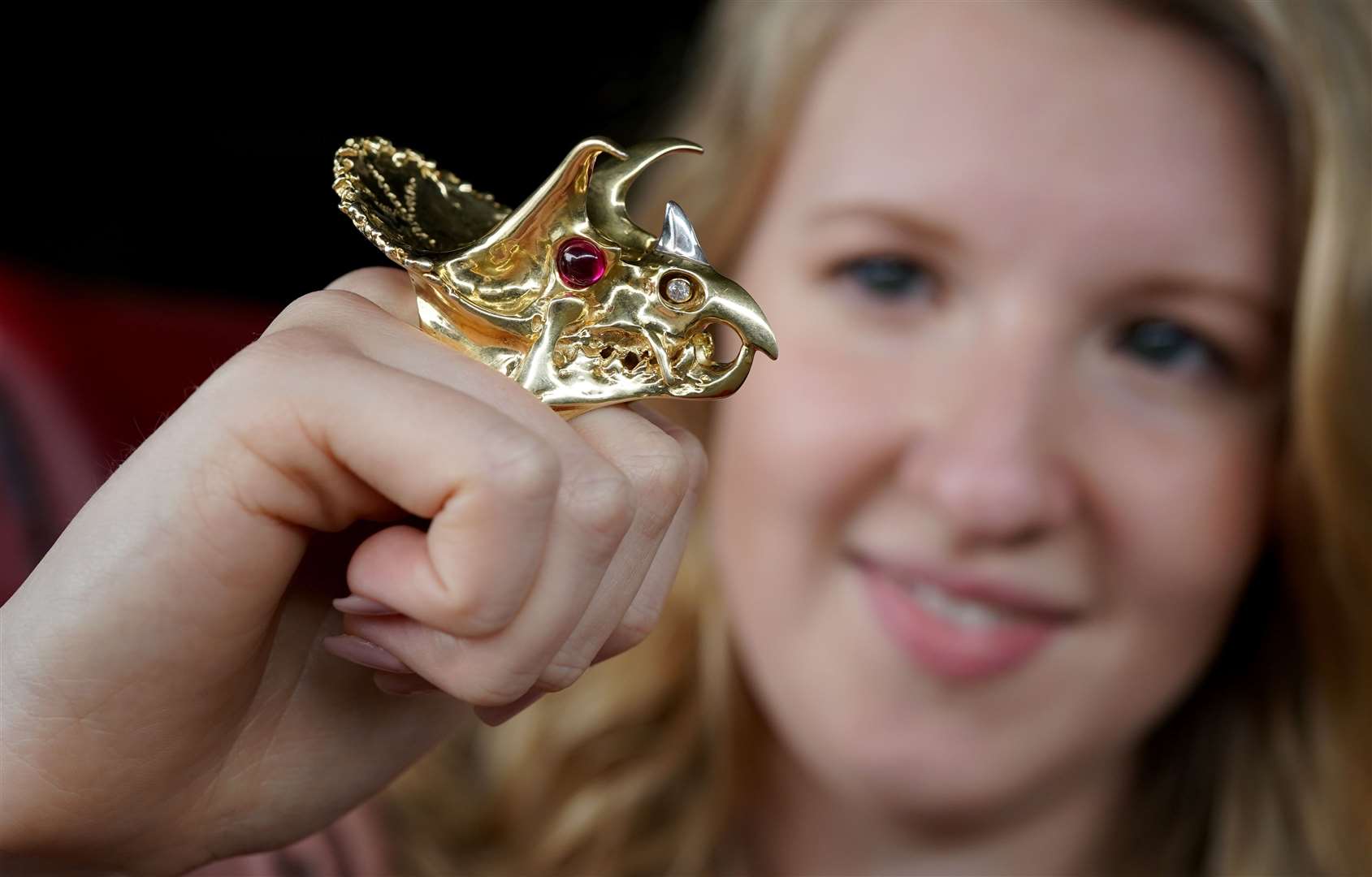 Annabel Winship of Bellmans auction house in West Sussex, wears an 18ct gold ring with diamonds and cabochon rubies designed as the head of a triceratops (Gareth Fuller/PA)