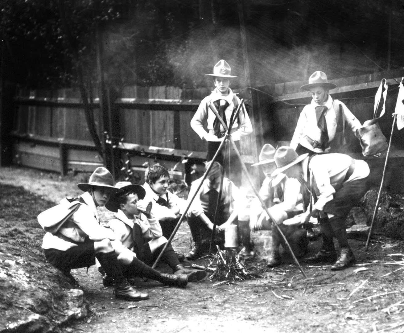 A group of Boy Scouts sitting around a camp fire in 1910 (PA)