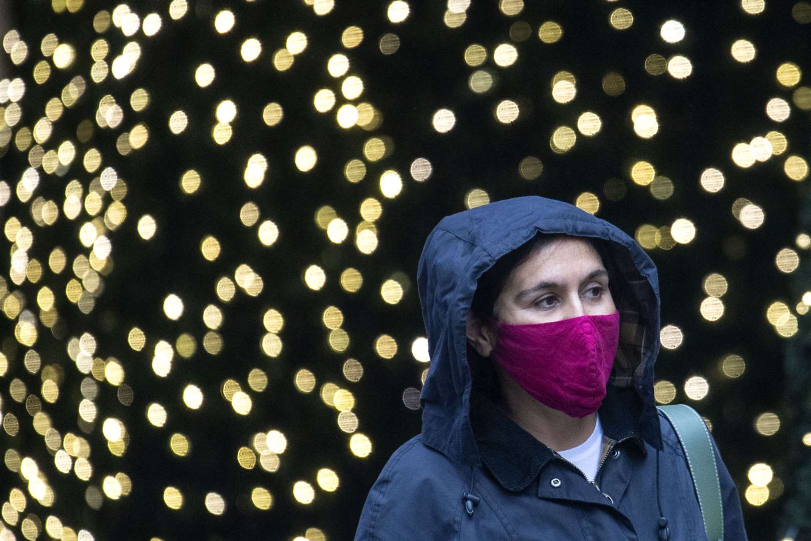 A shopper walks past Christmas lights in central London (Dominic Lipinski/PA)