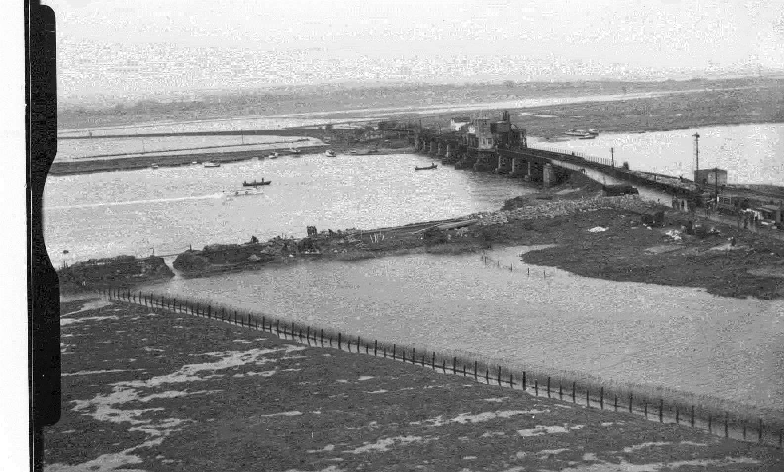 Flood water being drained from the land by means of cuts in the river wall near Kingsferry Bridge in 1953