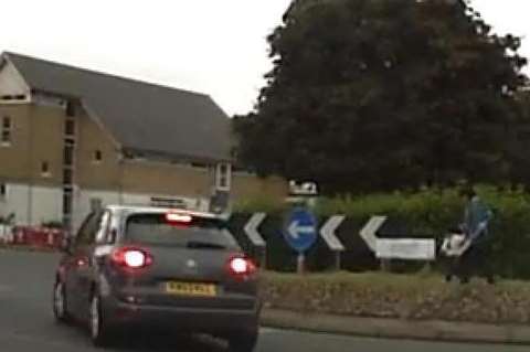 With the toddler clutching her hand, the woman crosses the grassy roundabout