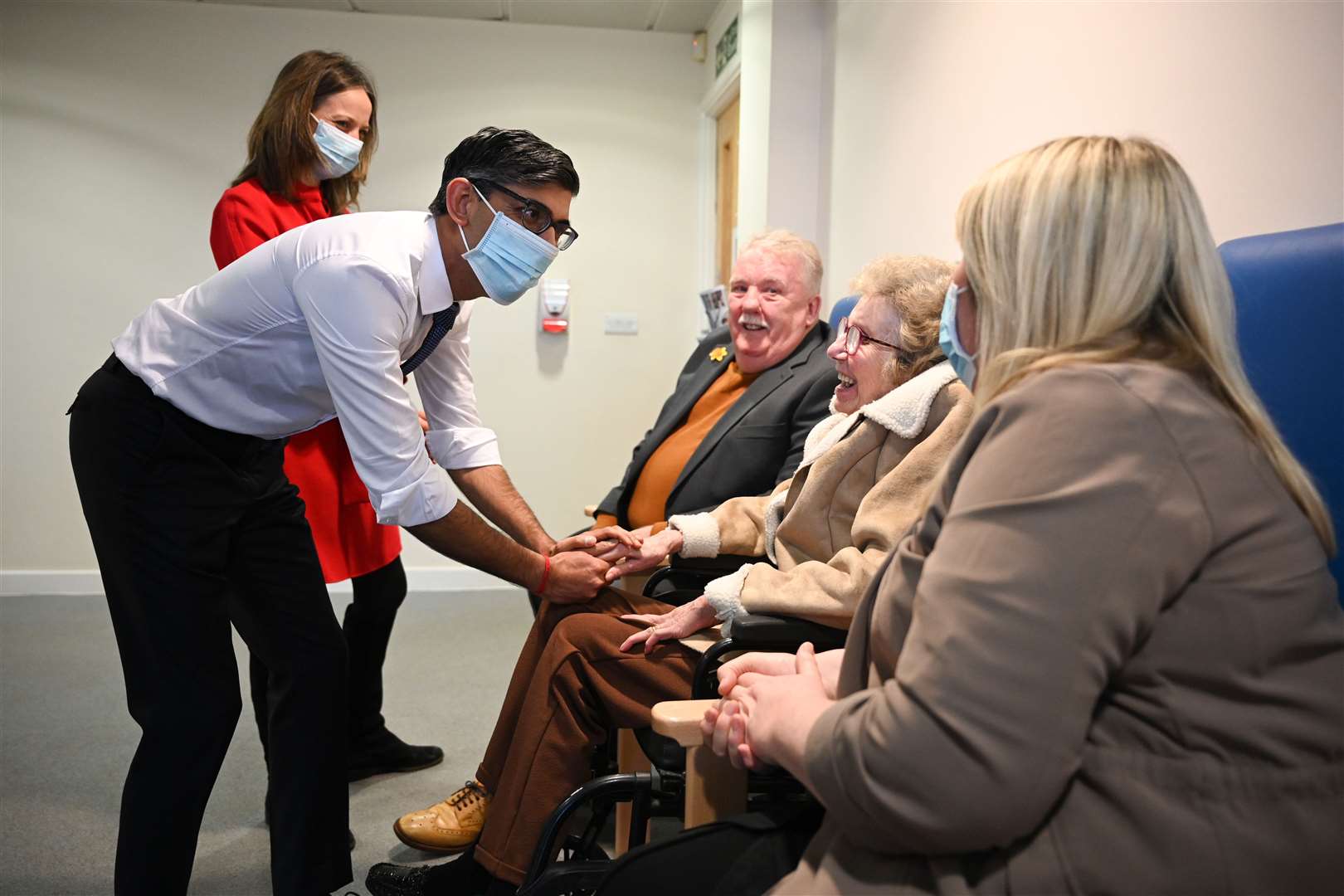 Mr Sunak, wearing a face mask, meets with a patient, centre, and her family during his visit to the medical centre (Oli Scarff/PA)