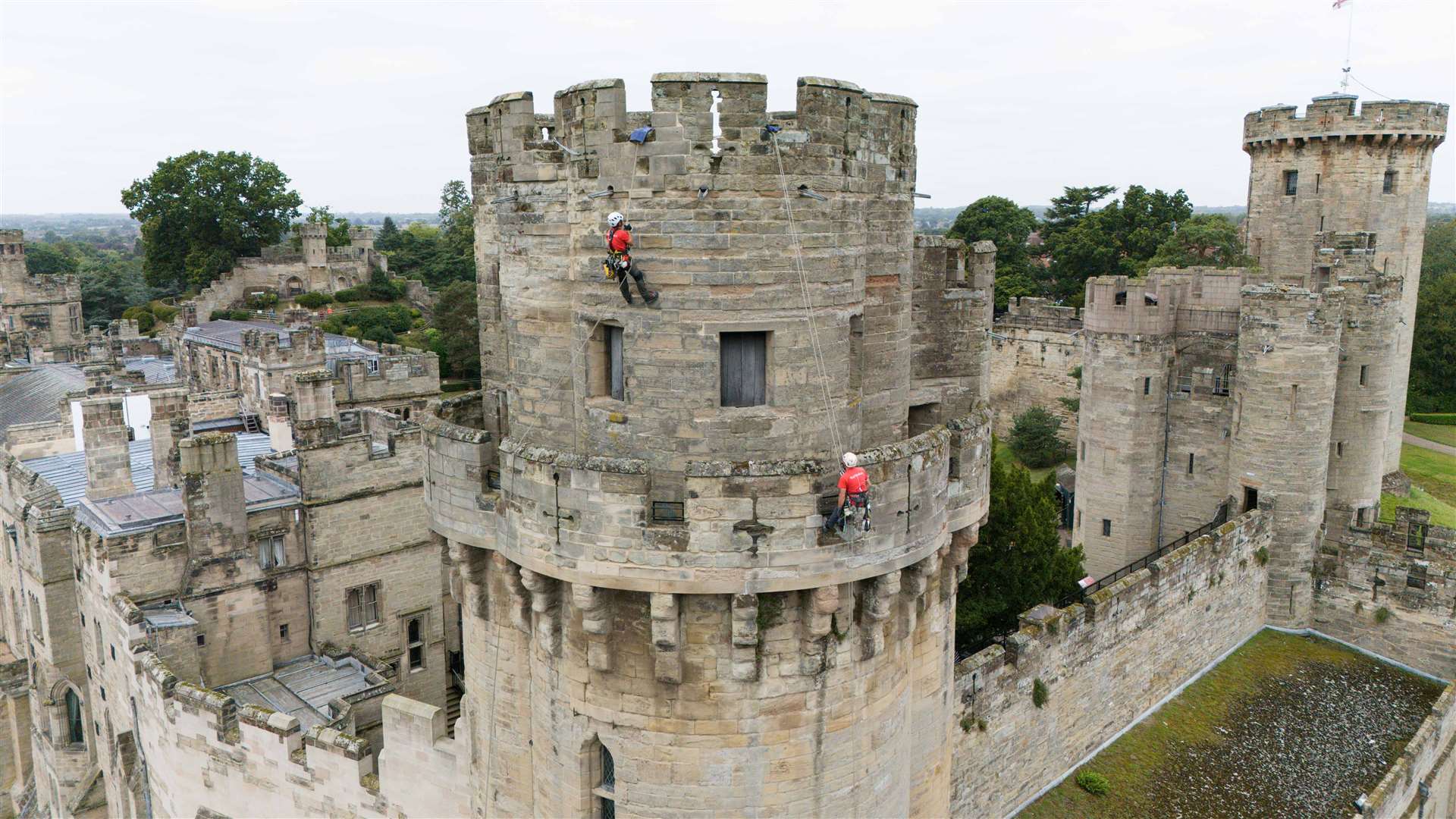 Building restoration specialists abseil from the top of Warwick Castle’s south front (Jacob King/PA)