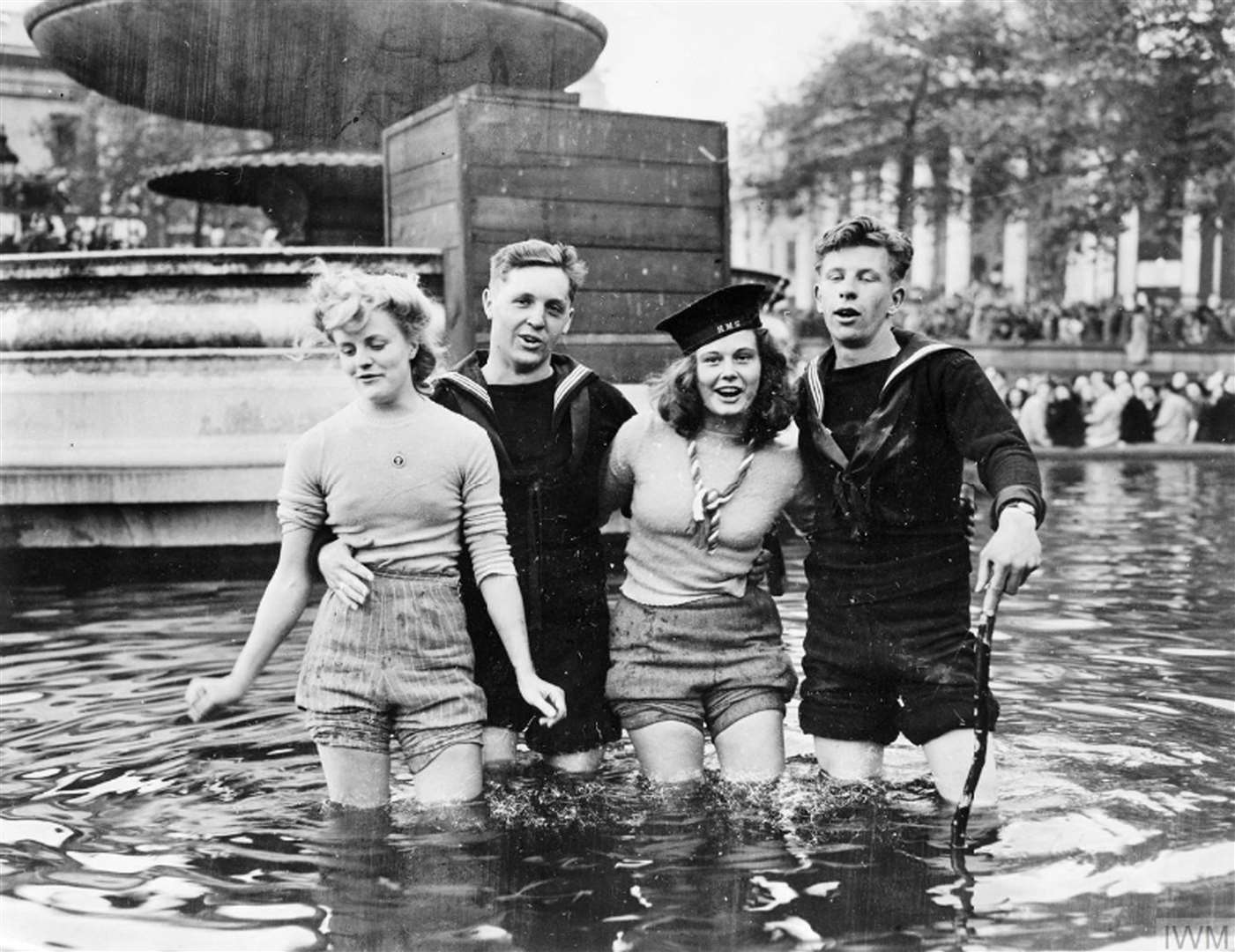 Two British sailors in a fountain in Trafalgar Square, London, with Joyce Digney (left) and Cynthia Covello, members of the Land Army (Imperial War Museum/PA)