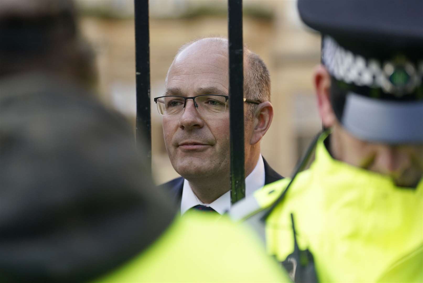 Tom Bradshaw, president of the National Farmers’ Union, talks to protesting farmers through gates outside the Oxford Farming Conference (Andrew Matthews/PA)