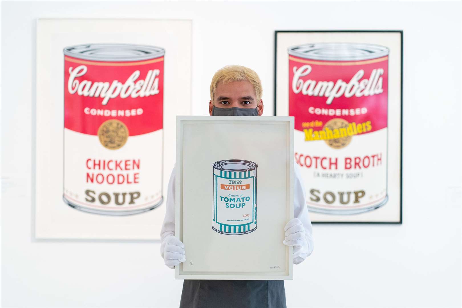 A Christie’s employee holds Soup Can – White/Emerald/Tan by Banksy (Dominic Lipinski/PA)