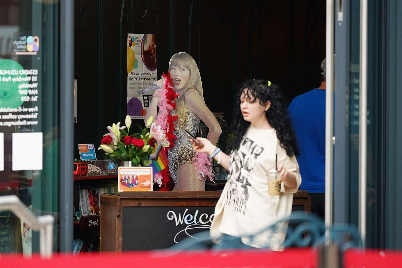 A Swiftie walks past a Taylor Swift cardboard cut-out in a cafe near Wembley Stadium (Yui Mok/PA)