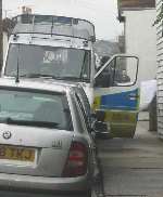 A man is taken to a police van covered by a sheet