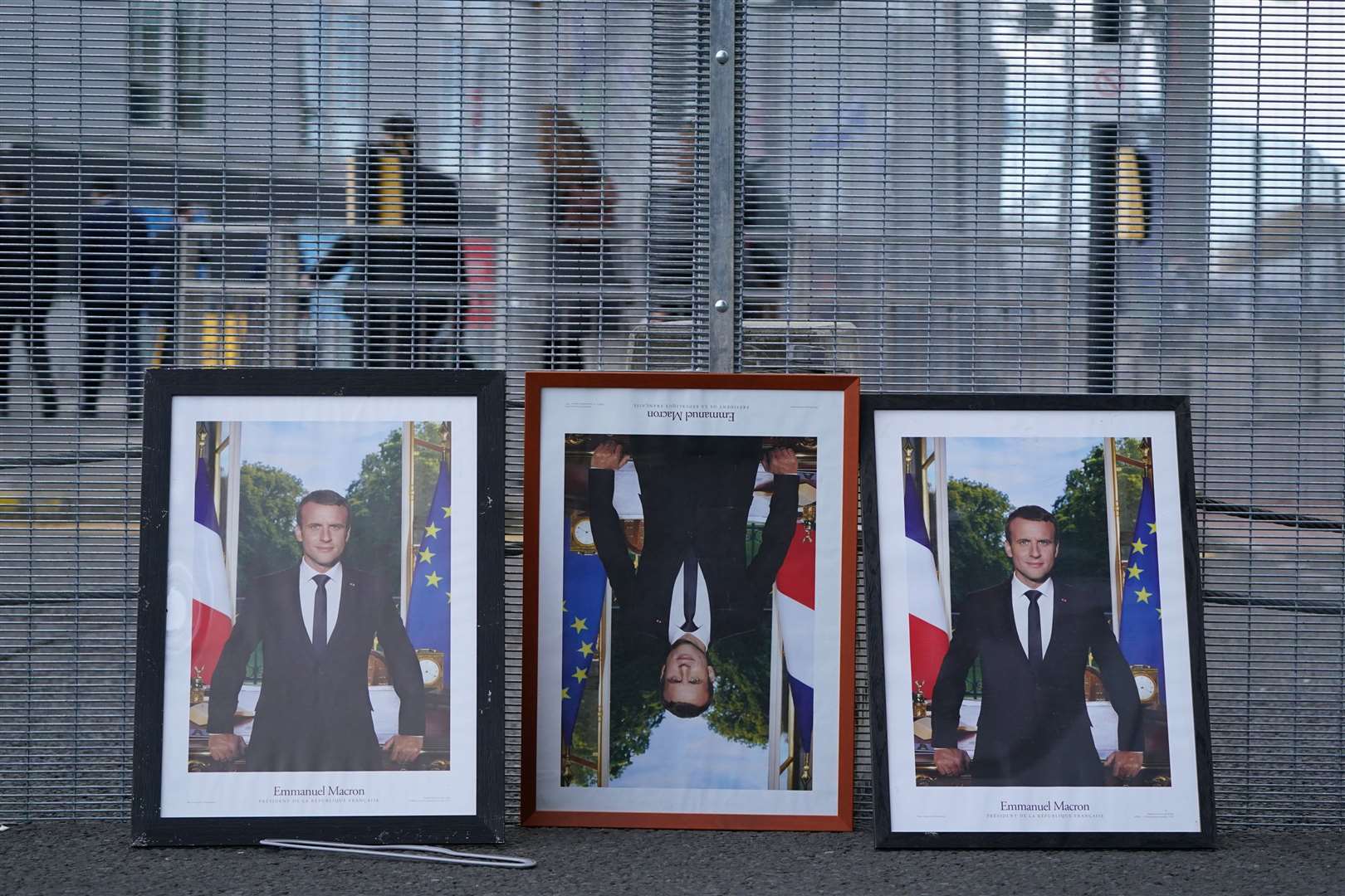 Three framed photographs of French President Emmanuel Macron propped up along the fencing on the perimeter of the Cop26 summit in Glasgow (Andrew Milligan/PA)