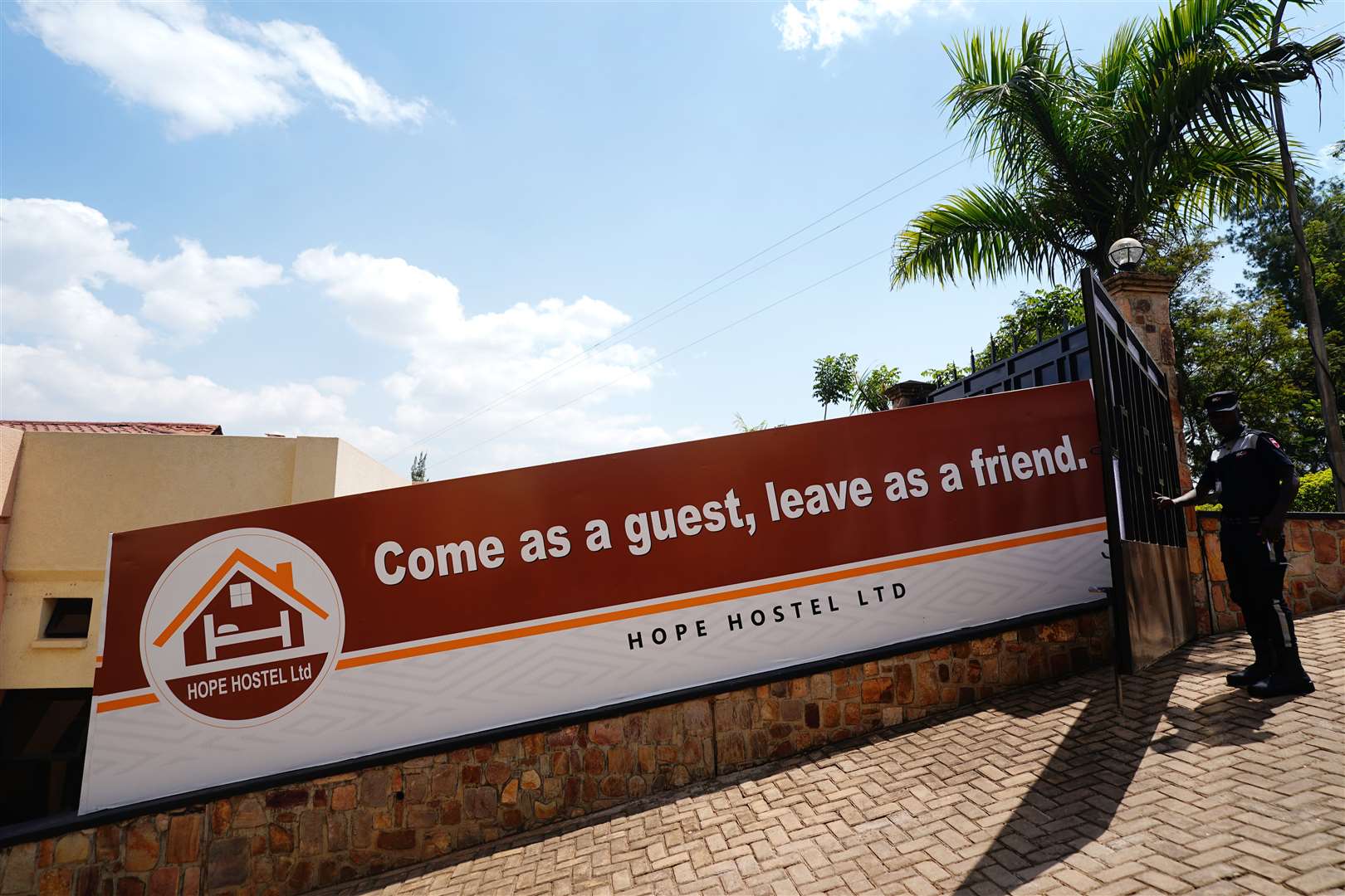 A security guard opens the entrance gate next to a sign reading ‘Come as a guest, leave as friend’ (Victoria Jones/PA)