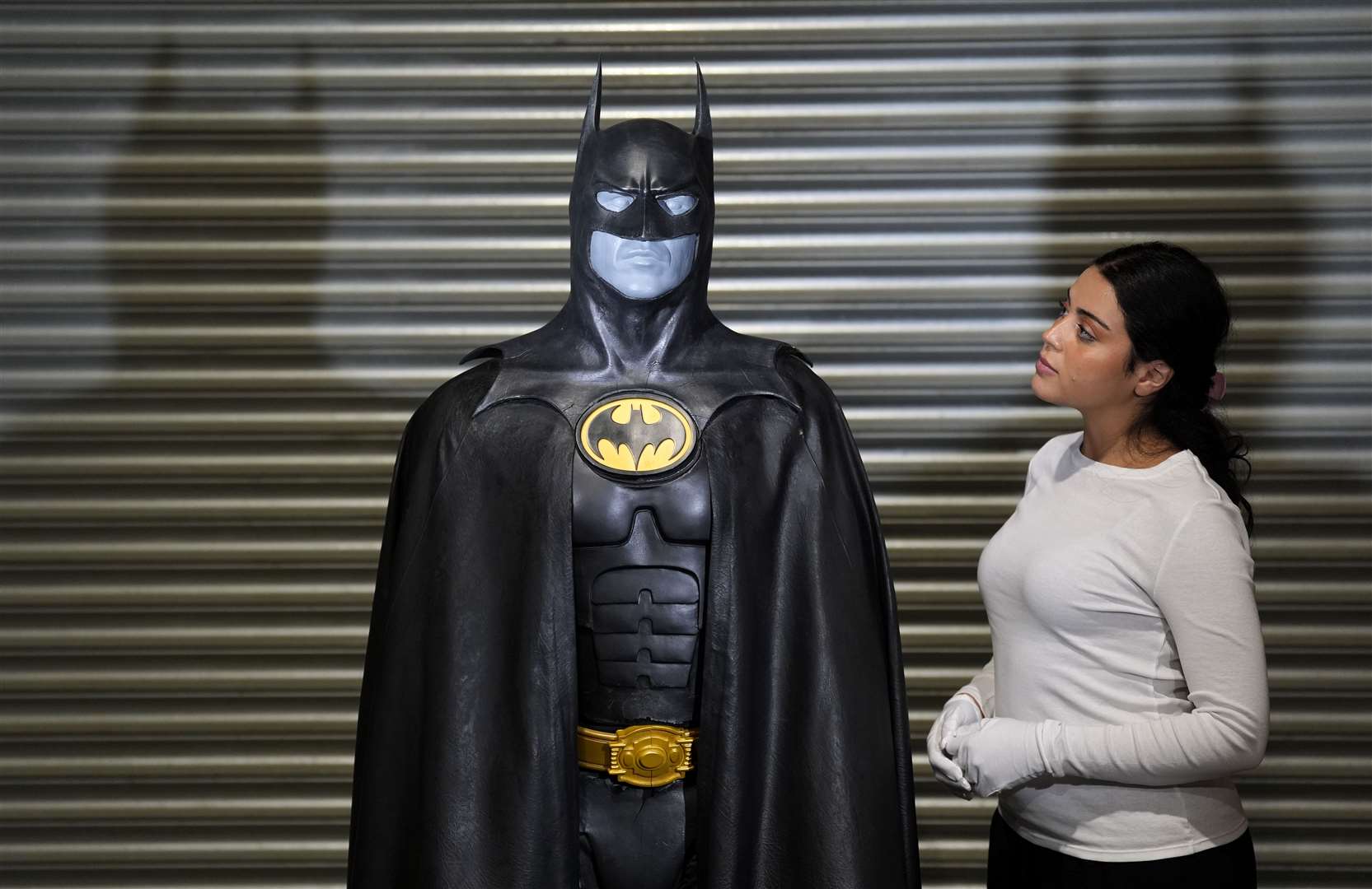 A Propstore employee looks up at Michael Keaton’s batsuit (Andrew Matthews/PA)