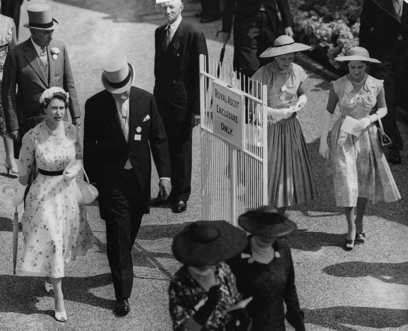 The Queen (left) and Princess Margaret (far right) walk to the paddock at the postponed Royal Ascot race meeting in July 1955 (PA)