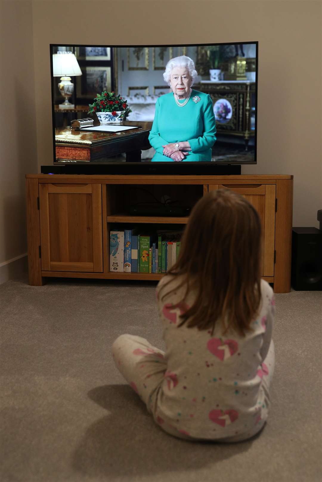 A young girl in Basingstoke, Hampshire, watches the Queen’s broadcast (PA)